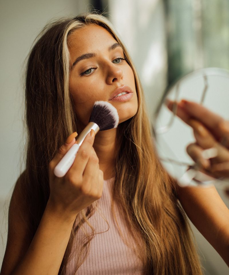 a young woman with oily skin applying makeup with a makeup brush