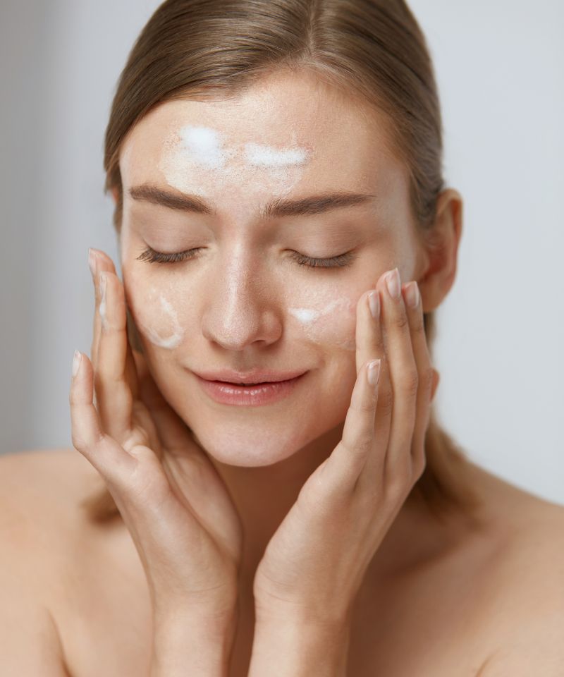 A woman with dry skin applying a gentle cleanser on her skin.