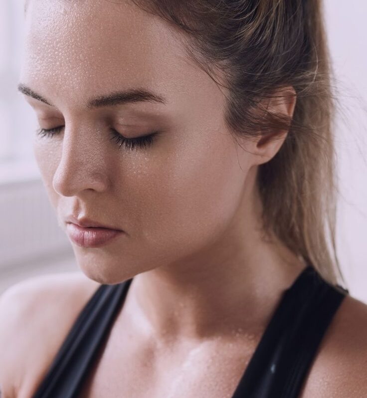 A sweaty woman with acne-free skin right after a workout.